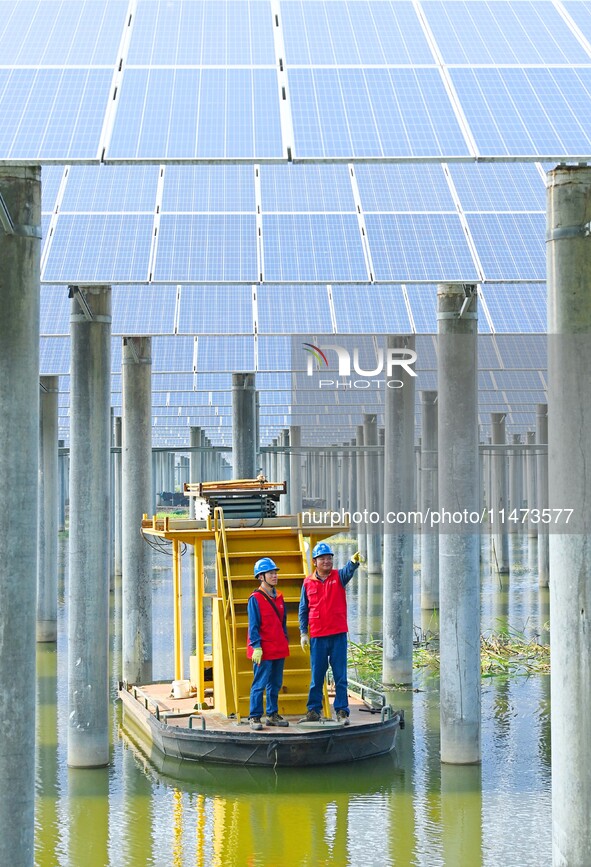 Operation and maintenance personnel are inspecting the operating power generation facilities at the ''fishery-solar hybrid project'' photovo...