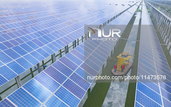 Operation and maintenance personnel are inspecting the operating power generation facilities at the ''fishery-solar hybrid project'' photovo...