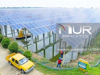 Operation and maintenance personnel are inspecting the operating power generation facilities at the ''fishery-solar hybrid project'' photovo...