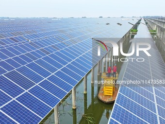 Operation and maintenance personnel are inspecting the operating power generation facilities at the ''fishery-solar hybrid project'' photovo...