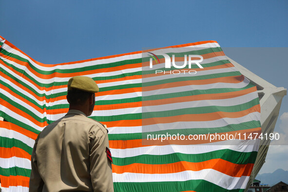 An Indian Policeman is looking at the Indoor stadium building with a giant Indian tri-color ahead of India's Independence Day celebrations i...