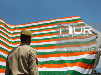 An Indian Policeman is looking at the Indoor stadium building with a giant Indian tri-color ahead of India's Independence Day celebrations i...