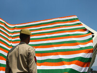 An Indian Policeman is looking at the Indoor stadium building with a giant Indian tri-color ahead of India's Independence Day celebrations i...