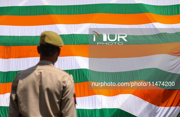 An Indian Policeman is looking at the Indoor stadium building with a giant Indian tri-color ahead of India's Independence Day celebrations i...