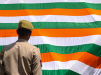 An Indian Policeman is looking at the Indoor stadium building with a giant Indian tri-color ahead of India's Independence Day celebrations i...