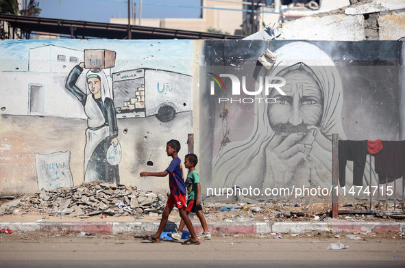 Displaced Palestinians are walking near their tents at a makeshift displacement camp set up on a roadside in Deir el-Balah in the central Ga...