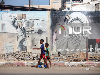 Displaced Palestinians are walking near their tents at a makeshift displacement camp set up on a roadside in Deir el-Balah in the central Ga...