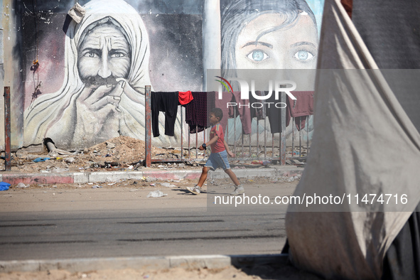 Displaced Palestinians are walking near their tents at a makeshift displacement camp set up on a roadside in Deir el-Balah in the central Ga...