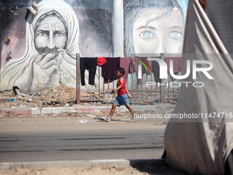 Displaced Palestinians are walking near their tents at a makeshift displacement camp set up on a roadside in Deir el-Balah in the central Ga...