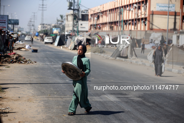 Displaced Palestinians are walking near their tents at a makeshift displacement camp set up on a roadside in Deir el-Balah in the central Ga...