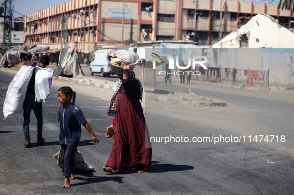 Displaced Palestinians are walking near their tents at a makeshift displacement camp set up on a roadside in Deir el-Balah in the central Ga...