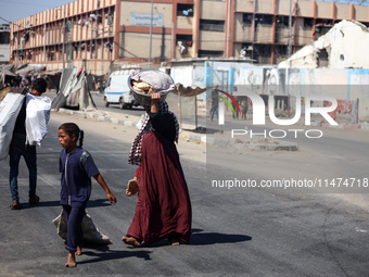 Displaced Palestinians are walking near their tents at a makeshift displacement camp set up on a roadside in Deir el-Balah in the central Ga...