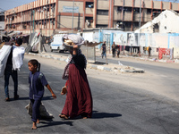 Displaced Palestinians are walking near their tents at a makeshift displacement camp set up on a roadside in Deir el-Balah in the central Ga...