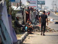 Displaced Palestinians are sitting by their tents at a makeshift displacement camp set up on a roadside in Deir el-Balah in the central Gaza...