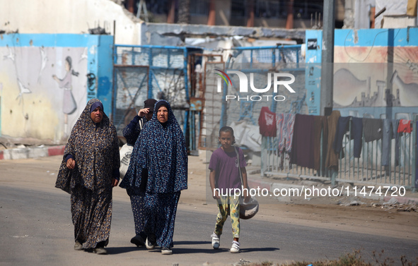 Displaced Palestinians are walking near their tents at a makeshift displacement camp set up on a roadside in Deir el-Balah in the central Ga...