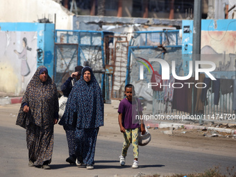 Displaced Palestinians are walking near their tents at a makeshift displacement camp set up on a roadside in Deir el-Balah in the central Ga...