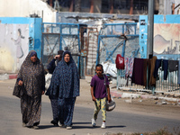 Displaced Palestinians are walking near their tents at a makeshift displacement camp set up on a roadside in Deir el-Balah in the central Ga...