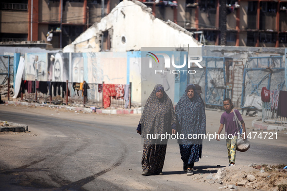 Displaced Palestinians are walking near their tents at a makeshift displacement camp set up on a roadside in Deir el-Balah in the central Ga...