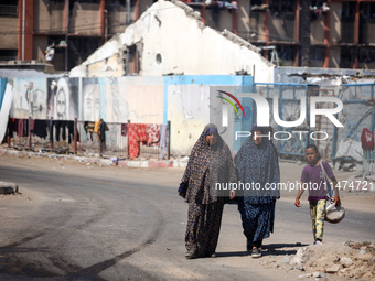 Displaced Palestinians are walking near their tents at a makeshift displacement camp set up on a roadside in Deir el-Balah in the central Ga...