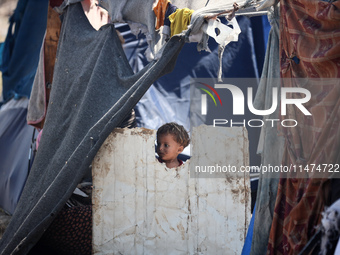 A Palestinian boy is looking outside a tent set on a road's median at a makeshift displacement camp set up along a road in Deir el-Balah in...