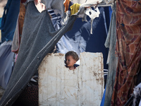 A Palestinian boy is looking outside a tent set on a road's median at a makeshift displacement camp set up along a road in Deir el-Balah in...