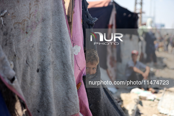 A Palestinian boy is looking outside a tent set on a road's median at a makeshift displacement camp set up along a road in Deir el-Balah in...