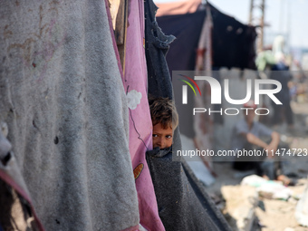 A Palestinian boy is looking outside a tent set on a road's median at a makeshift displacement camp set up along a road in Deir el-Balah in...