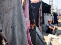 A Palestinian boy is looking outside a tent set on a road's median at a makeshift displacement camp set up along a road in Deir el-Balah in...