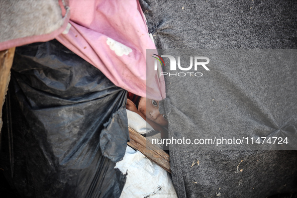 A Palestinian boy is looking outside a tent set on a road's median at a makeshift displacement camp set up along a road in Deir el-Balah in...