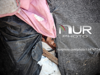 A Palestinian boy is looking outside a tent set on a road's median at a makeshift displacement camp set up along a road in Deir el-Balah in...