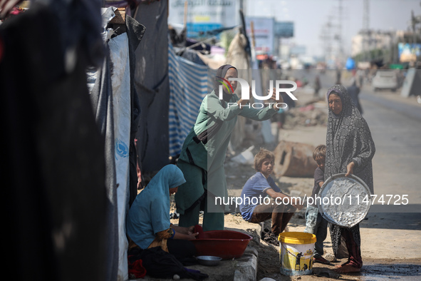 A Palestinian girl is carrying water at a makeshift displacement camp set up on a roadside in Deir el-Balah in the central Gaza Strip on Aug...