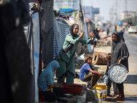 A Palestinian girl is carrying water at a makeshift displacement camp set up on a roadside in Deir el-Balah in the central Gaza Strip on Aug...