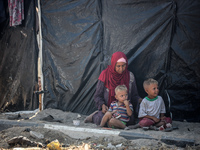 Displaced Palestinians are sitting by their tents at a makeshift displacement camp set up on a roadside in Deir el-Balah in the central Gaza...