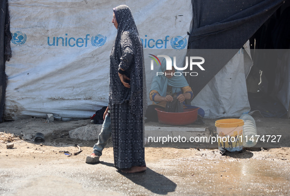 Displaced Palestinians are doing chores by their tents at a makeshift displacement camp set up on a roadside in Deir el-Balah in the central...