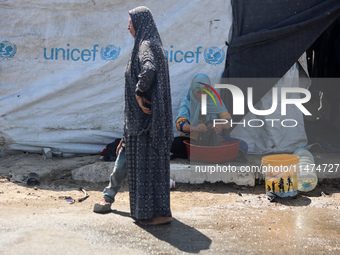 Displaced Palestinians are doing chores by their tents at a makeshift displacement camp set up on a roadside in Deir el-Balah in the central...