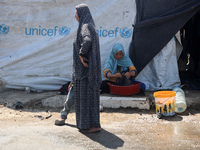 Displaced Palestinians are doing chores by their tents at a makeshift displacement camp set up on a roadside in Deir el-Balah in the central...