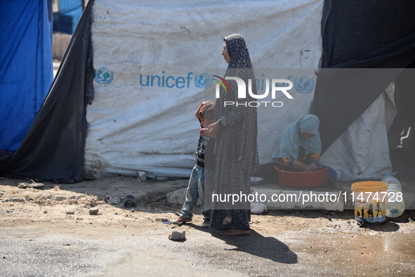 Displaced Palestinians are doing chores by their tents at a makeshift displacement camp set up on a roadside in Deir el-Balah in the central...