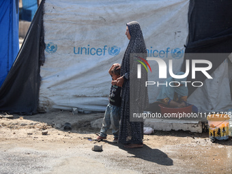 Displaced Palestinians are doing chores by their tents at a makeshift displacement camp set up on a roadside in Deir el-Balah in the central...