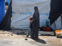 Displaced Palestinians are doing chores by their tents at a makeshift displacement camp set up on a roadside in Deir el-Balah in the central...