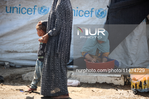 Displaced Palestinians are doing chores by their tents at a makeshift displacement camp set up on a roadside in Deir el-Balah in the central...