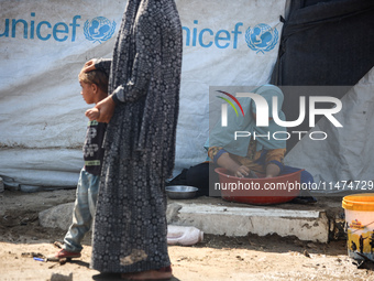 Displaced Palestinians are doing chores by their tents at a makeshift displacement camp set up on a roadside in Deir el-Balah in the central...