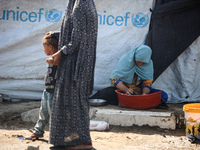 Displaced Palestinians are doing chores by their tents at a makeshift displacement camp set up on a roadside in Deir el-Balah in the central...