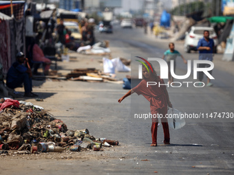 A Palestinian girl is carrying water at a makeshift displacement camp set up on a roadside in Deir el-Balah in the central Gaza Strip on Aug...