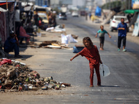 A Palestinian girl is carrying water at a makeshift displacement camp set up on a roadside in Deir el-Balah in the central Gaza Strip on Aug...