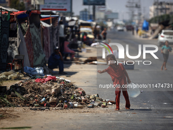 A Palestinian girl is carrying water at a makeshift displacement camp set up on a roadside in Deir el-Balah in the central Gaza Strip on Aug...