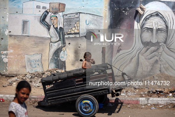 A boy is reacting as he is sitting in the back of a trailer at a makeshift displacement camp set up on a roadside in Deir el-Balah in the ce...