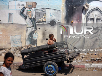 A boy is reacting as he is sitting in the back of a trailer at a makeshift displacement camp set up on a roadside in Deir el-Balah in the ce...