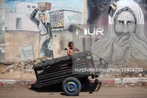 A boy is reacting as he is sitting in the back of a trailer at a makeshift displacement camp set up on a roadside in Deir el-Balah in the ce...