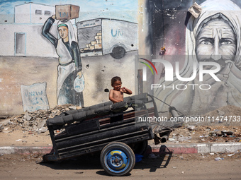 A boy is reacting as he is sitting in the back of a trailer at a makeshift displacement camp set up on a roadside in Deir el-Balah in the ce...