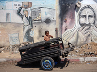 A boy is reacting as he is sitting in the back of a trailer at a makeshift displacement camp set up on a roadside in Deir el-Balah in the ce...